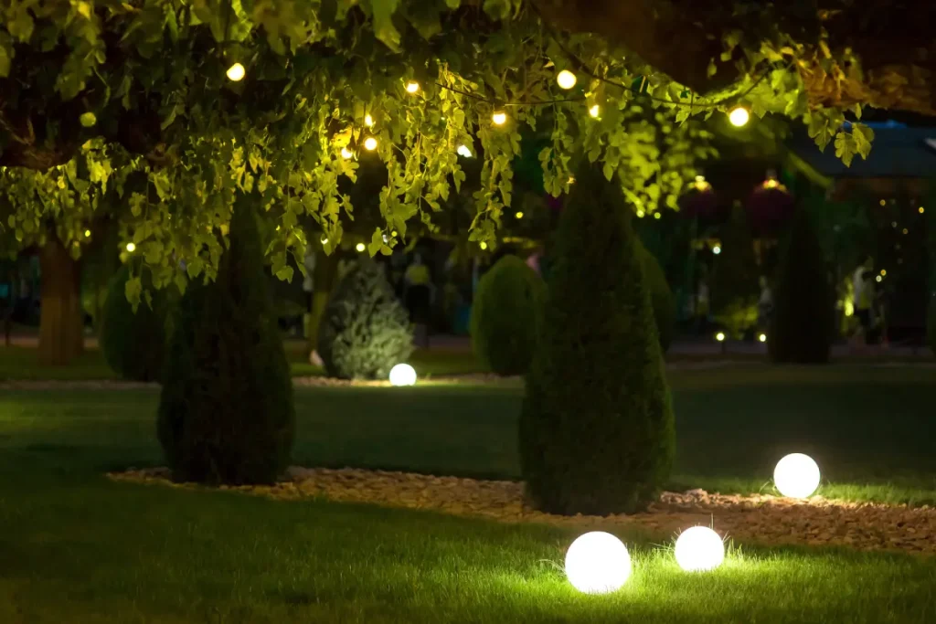 Auf dem Rasen im Garten stehen leuchtende Kugellampen.